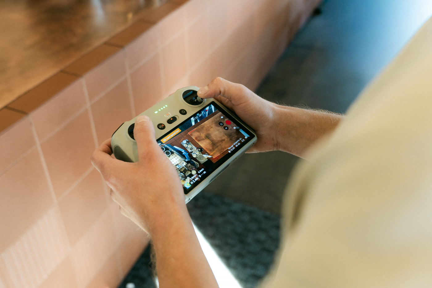 The drone's controller held in two hands, the live view of the cafe's interior on its screen