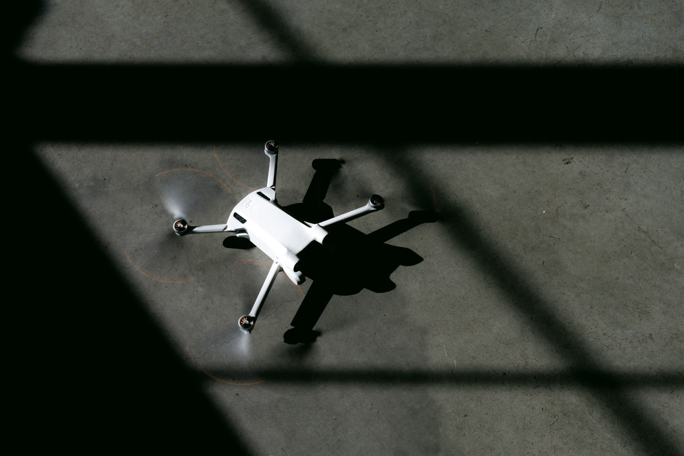 The drone at rest on the cafe's concrete floor, the grid shadow of a window laid across it