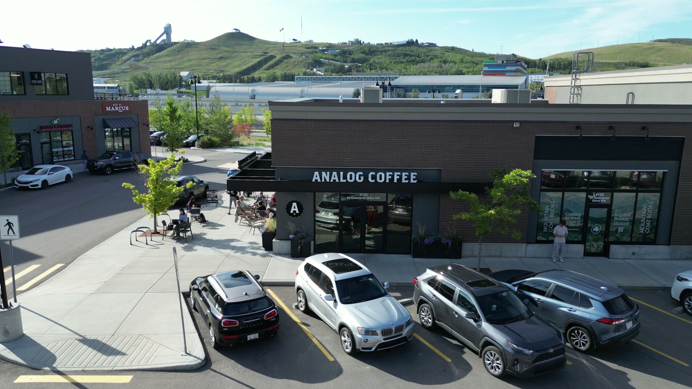 The storefront from straight on with the green hill and its ski jump tower over the roofline behind