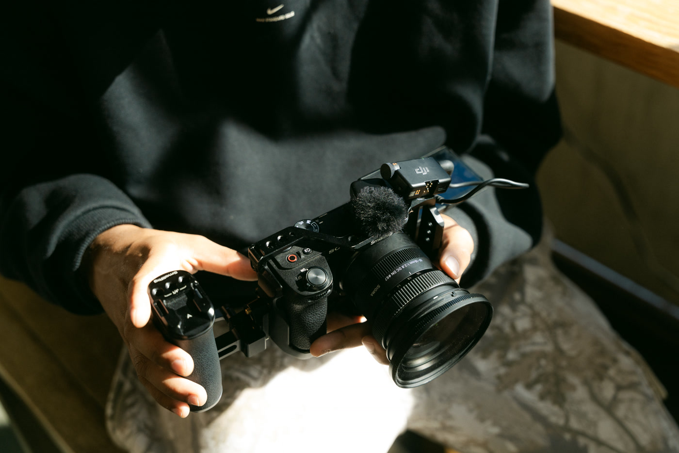 A camera with a shotgun microphone on top held out in one hand inside the cafe