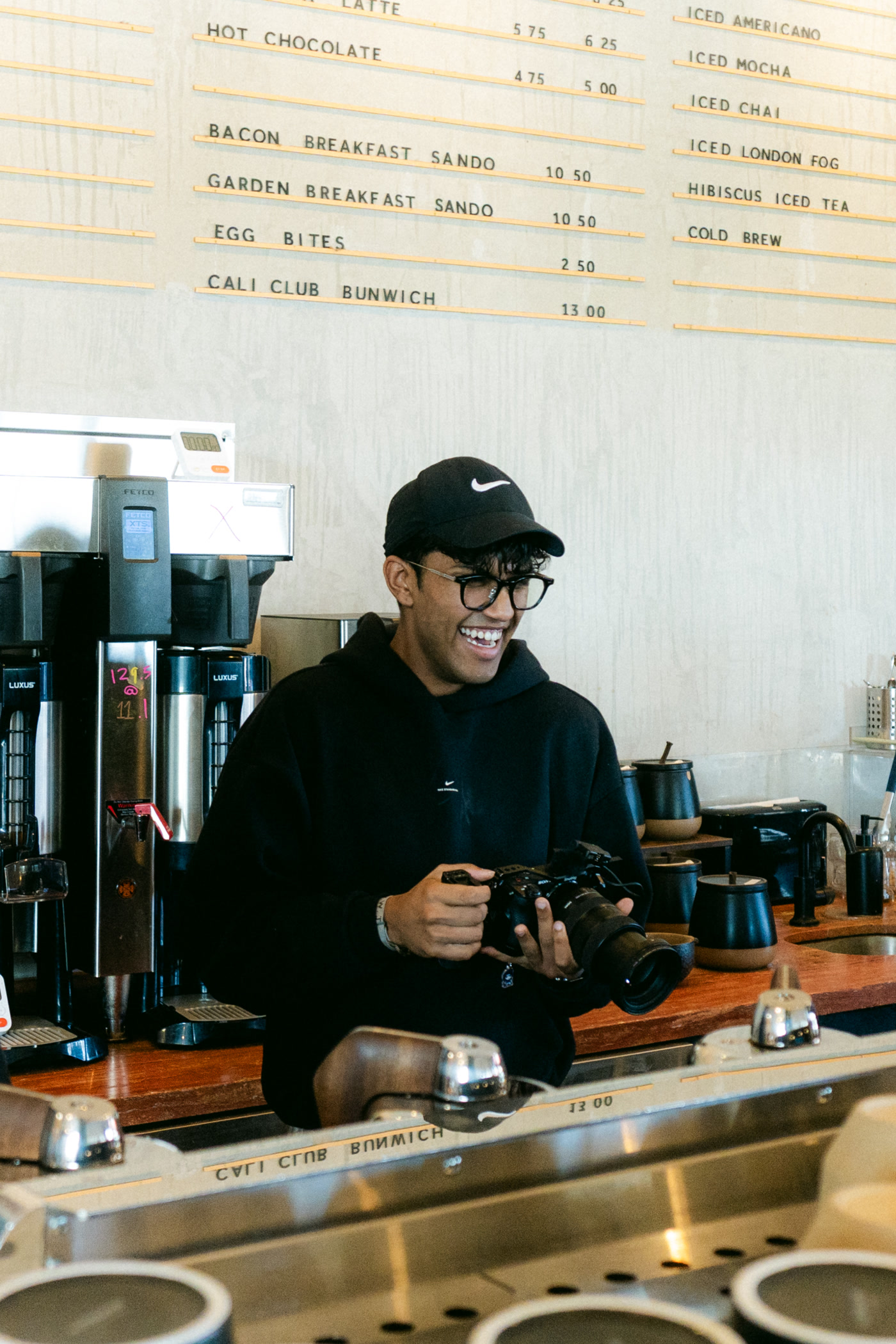 The letterboard menu in movable type: hot chocolate, bacon and garden breakfast sandos, egg bites, a Cali club bunwich, and the iced list beside them