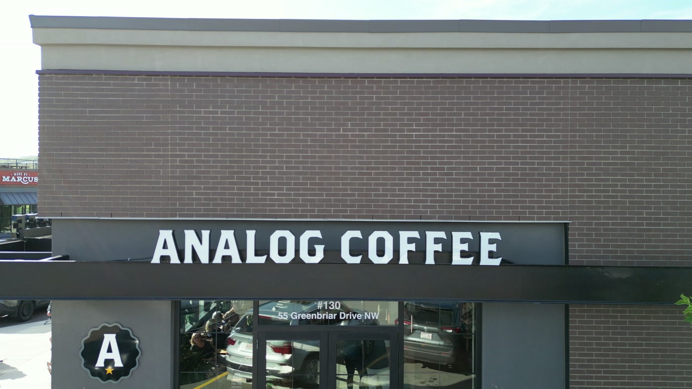 The ANALOG COFFEE fascia in white capitals over the doors, the A roundel beside them and 55 Greenbriar Drive NW on the glass