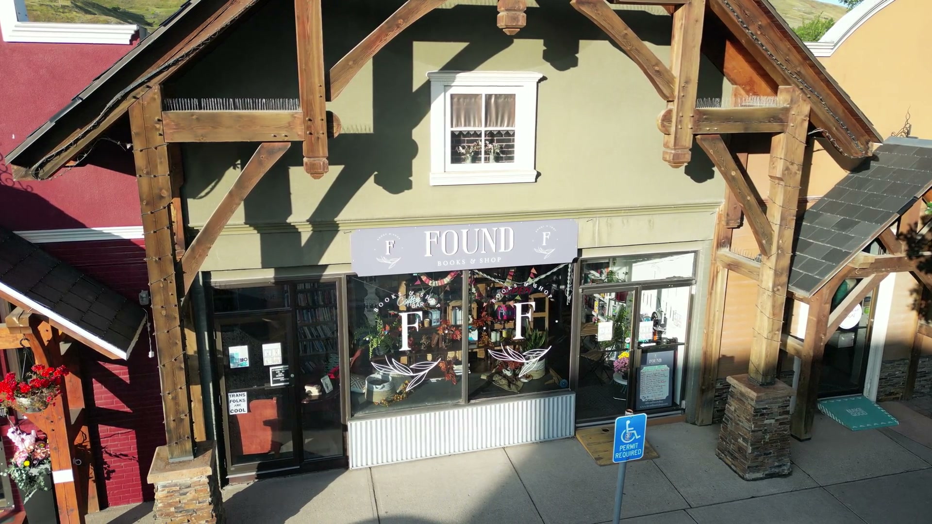 The painted board reading FOUND under the timber gable of Found Books & Shop in Cochrane, the camera sliding left to right across the shopfront and its two F monograms