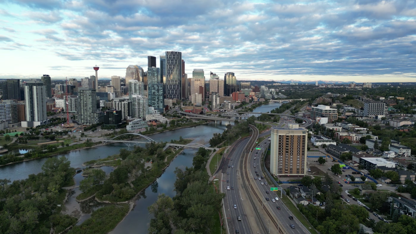 Downtown Calgary from above Bridgeland: the George C. King Bridge to St. Patrick's Island, the CTrain along Memorial Drive, the bridges upstream, the Calgary Tower and The Bow, the Rockies on the horizon