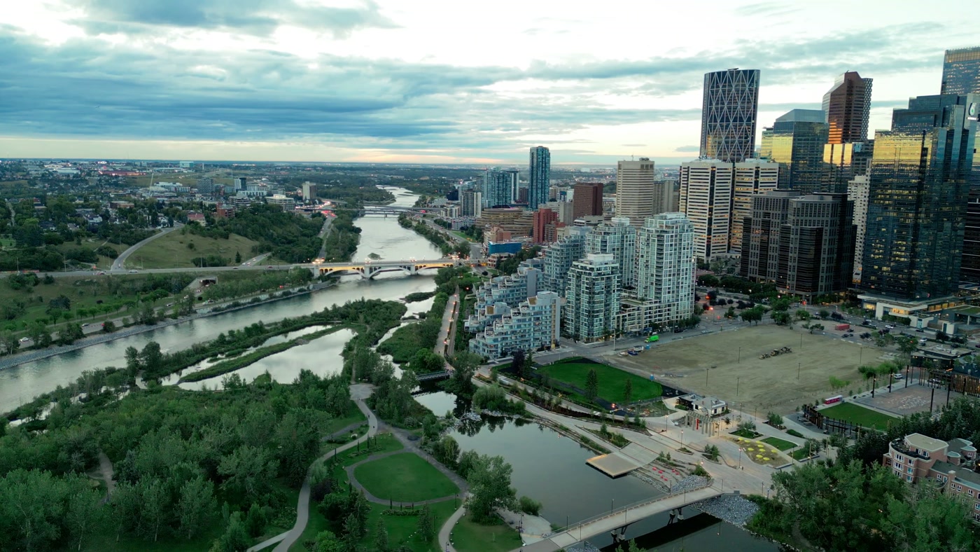 The wetland ponds at the east end of Prince's Island at dusk, the footbridge and lit promenade to Eau Claire, the towers of downtown above