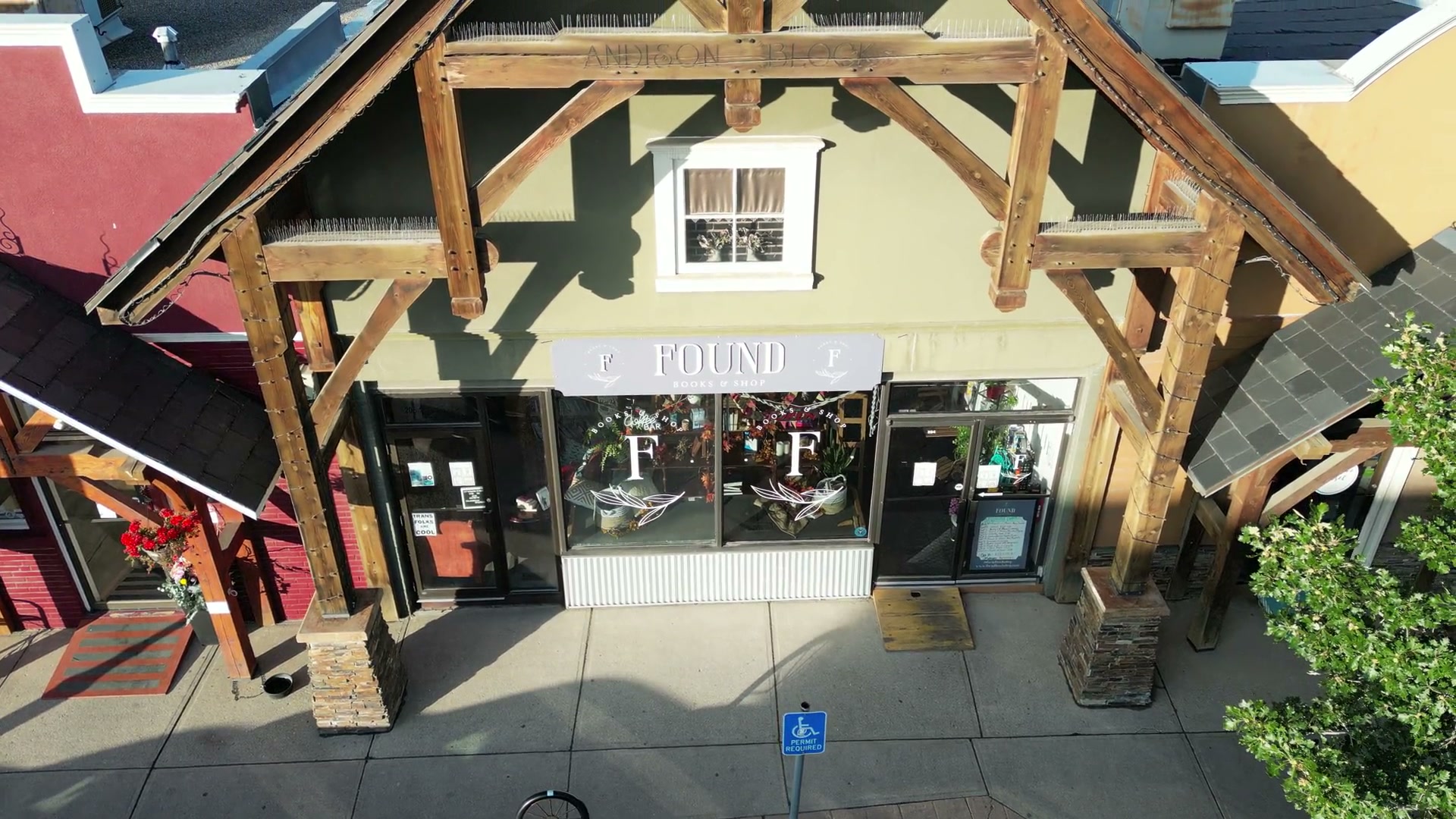 The camera rising off the timber gable of Found Books & Shop in Cochrane and moving right, the roofs of the block coming up behind it