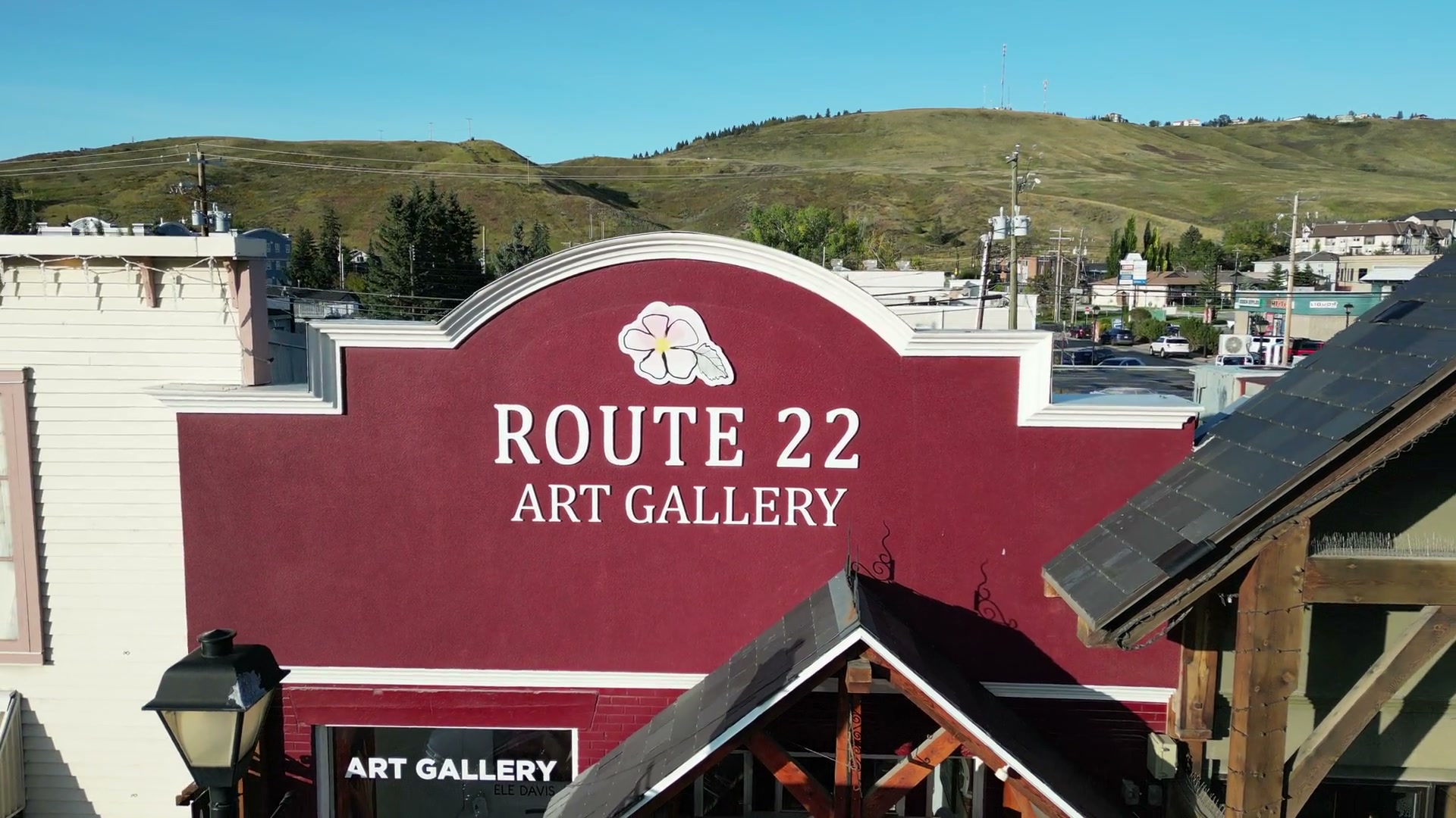 Held on the red parapet of Route 22 Art Gallery in Cochrane, the foothills standing behind the roofline