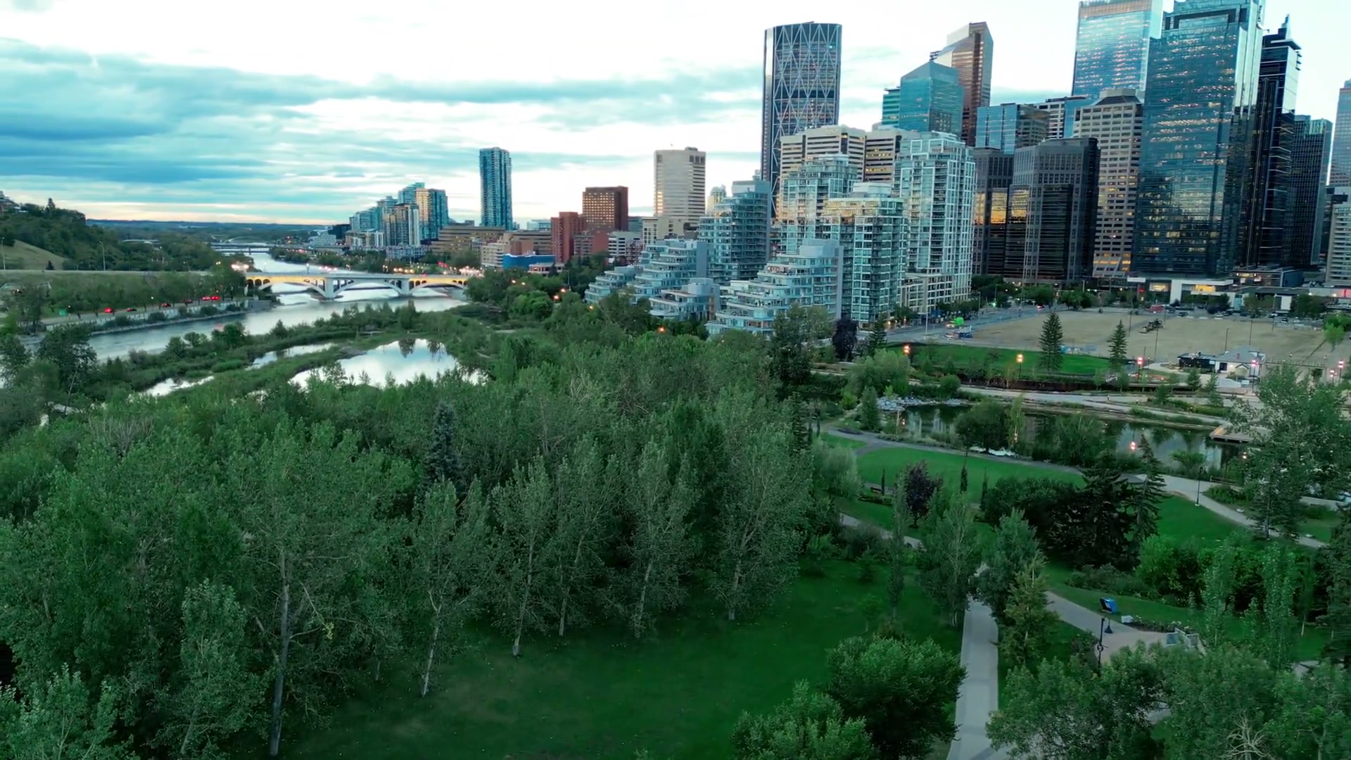 East along the Bow River from above Prince's Island Park at dusk: the wetland below, the Eau Claire towers to the right, the Centre Street Bridge ahead