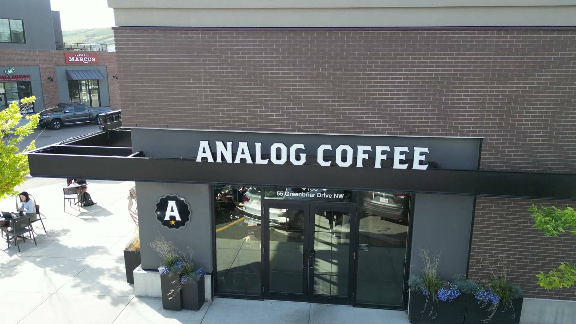 Rising from the café's patio past the black awning and the lettering on the brick
