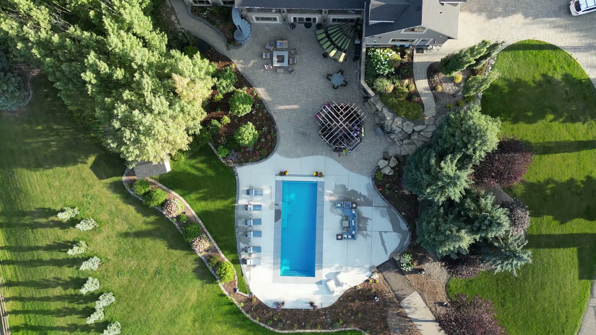 The estate's swimming pool and terrace seen from directly above, framed by spruce and lawn