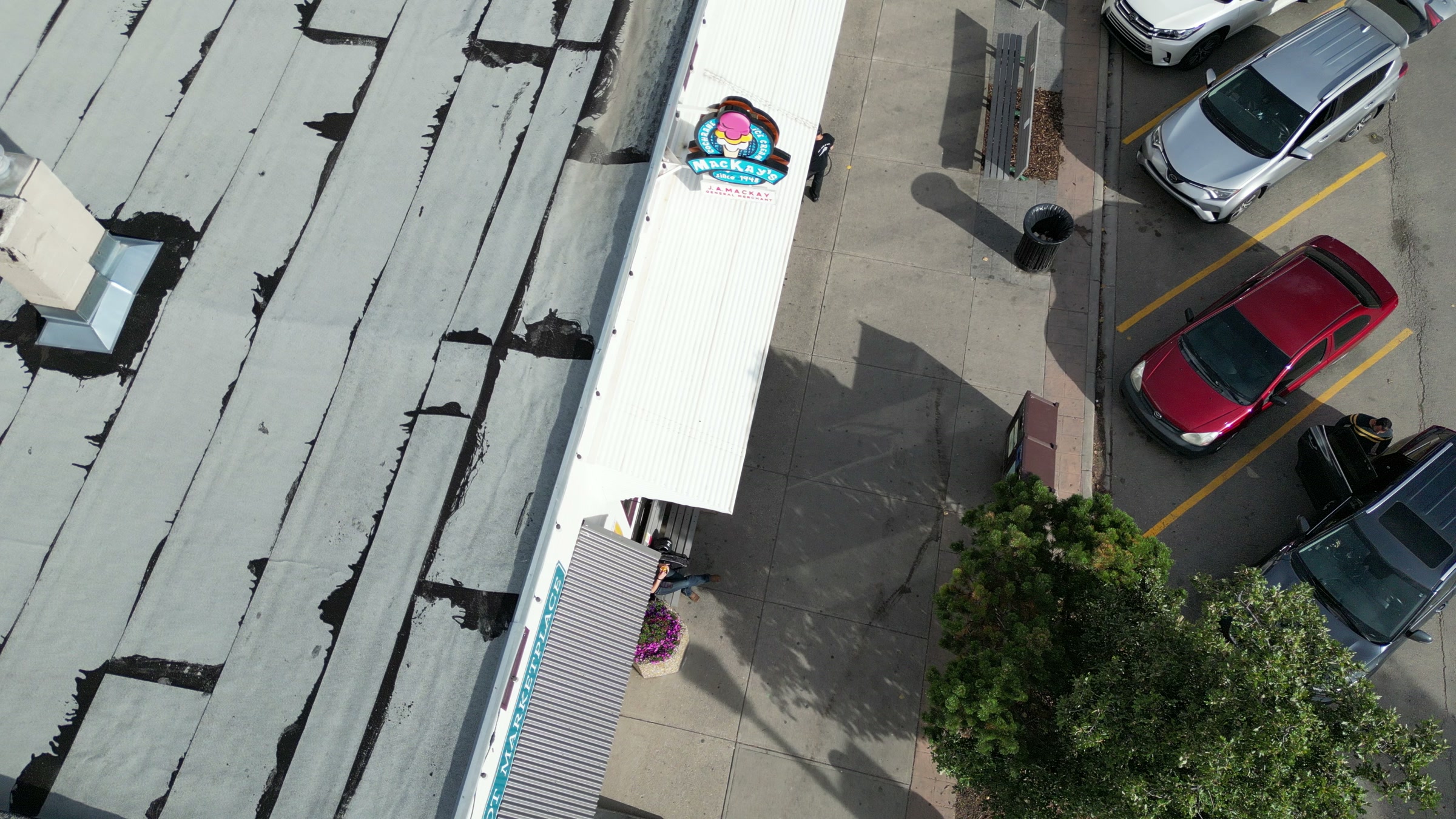 The roof and awning of an ice cream shop from directly above, cars parked along the front