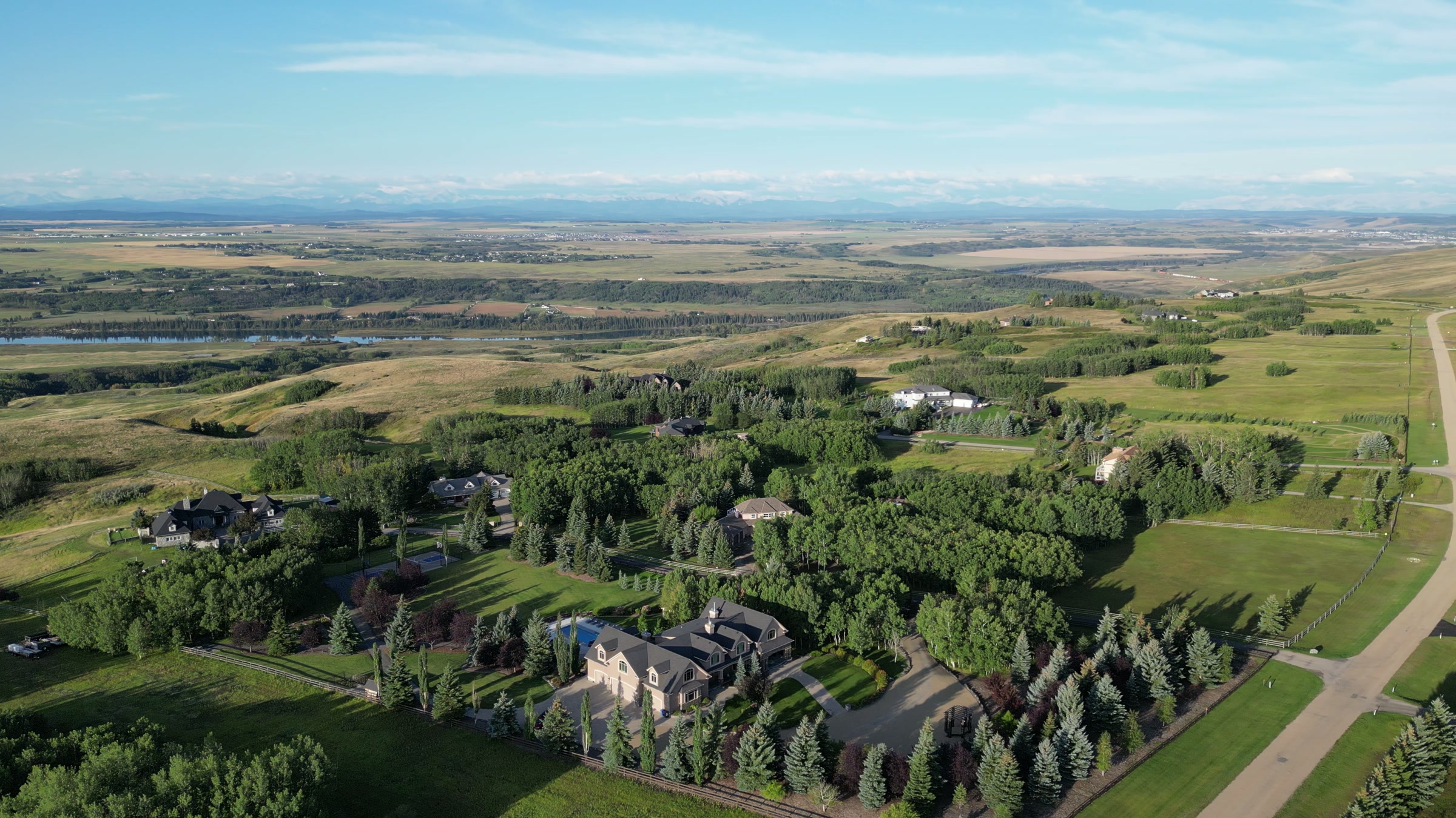 Open Alberta country stretching to the horizon beyond the estate's trees