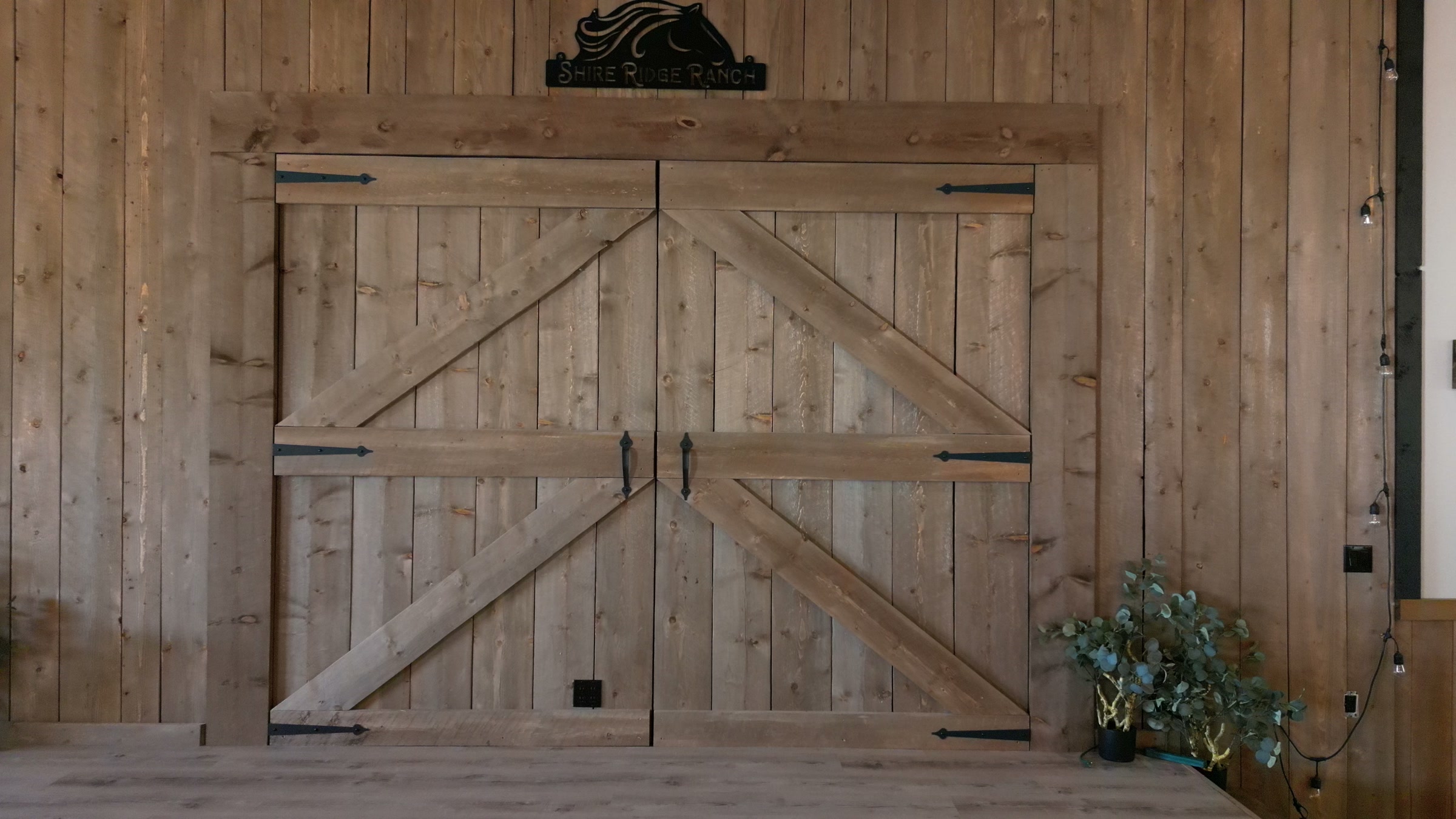 The barn doors behind the stage of the wedding hall, greenery either side
